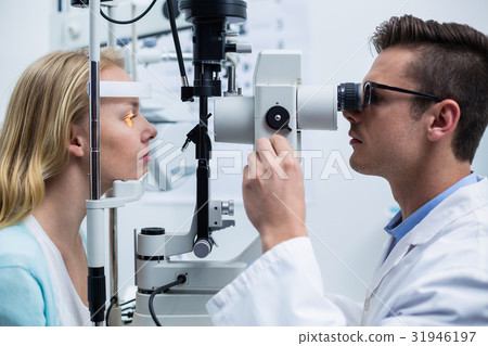 Optometrist examining female patient on slit lamp Optometrist examining female patient on slit lamp 31946197