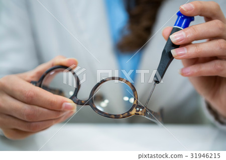 Optician repairing spectacles with tool 31946215