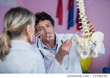 Physiotherapist explaining the spine model to patient Physiotherapist explaining the spine model to patient 31946296