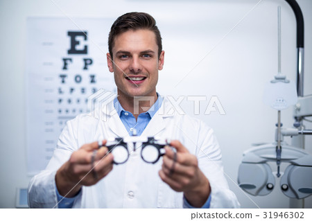 Smiling optometrist holding messbrille 31946302