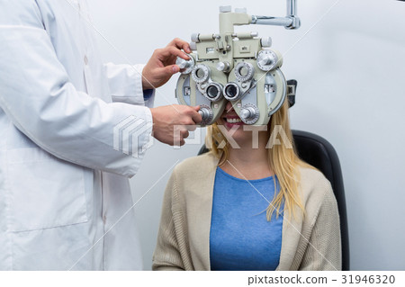 Optometrist examining female patient on phoropter Optometrist examining female patient on phoropter 31946320