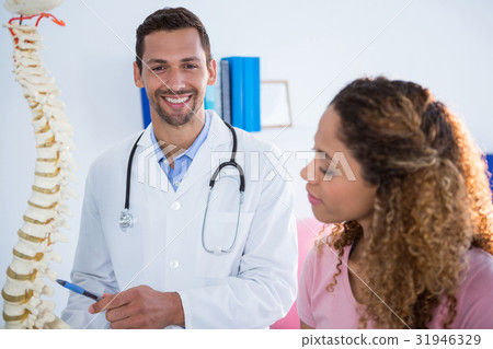 Physiotherapist explaining spine model to patient Physiotherapist explaining spine model to patient 31946329