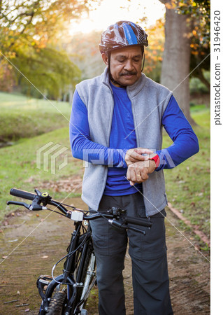 Man touching his watch next to his bike 31946420
