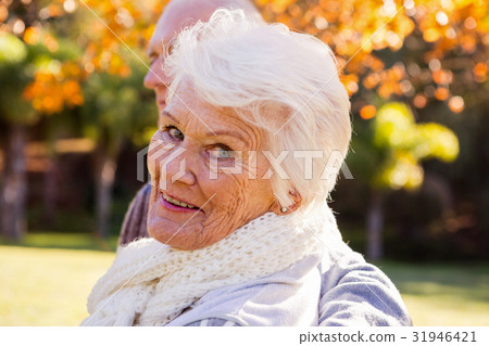 Portrait of a senior woman with her husband in background Portrait of a senior woman with her husband in background 31946421