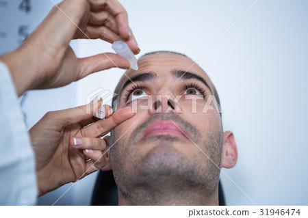 Optometrist putting drops into patients eyes Optometrist putting drops into patients eyes 31946474