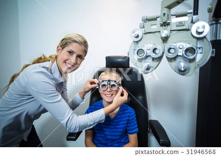 Female optometrist examining young patient with phoropter Female optometrist examining young patient with phoropter 31946568