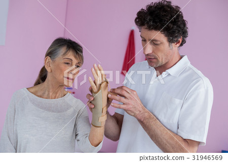 Physiotherapist examining a senior womans wrist Physiotherapist examining a senior womans wrist 31946569