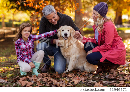 Smiling family with dog at park Smiling family with dog at park 31946571