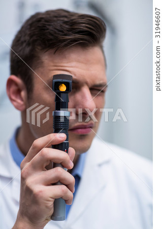 Close-up of optometrist looking through ophthalmoscope 31946607
