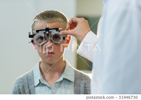 Optometrist examining young patient with phoropter Optometrist examining young patient with phoropter 31946730