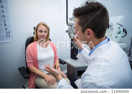 Optometrist assisting female patient 31946999