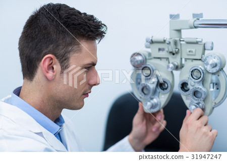 Attentive optometrist adjusting phoropter Attentive optometrist adjusting phoropter 31947247