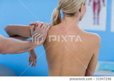 Male physiotherapist giving shoulder massage to female patient 31947296