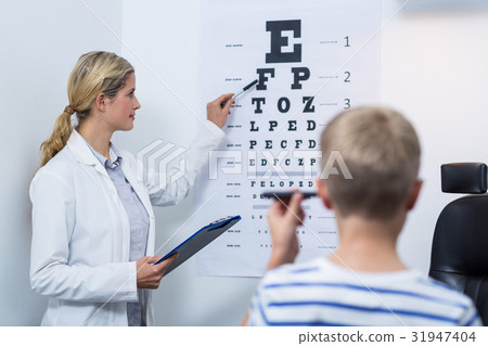 Female optometrist taking eye test of young patient 31947404