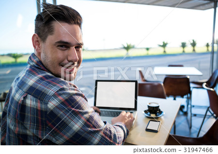 Man using his laptop in coffee shop Man using his laptop in coffee shop 31947466
