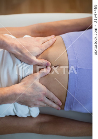 Male physiotherapist giving stomach massage to female patient 31947469