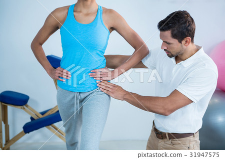 Physiotherapist examining womans back 31947575