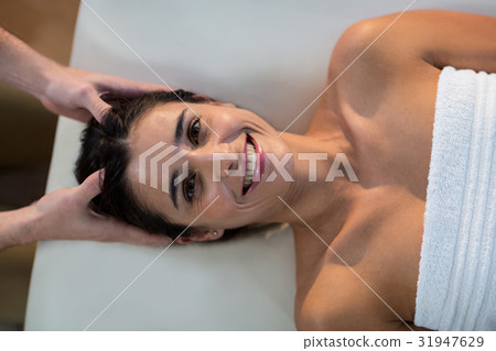 Male physiotherapist giving head massage to female patient 31947629