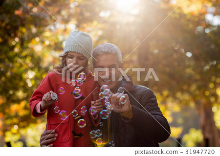 Father and daughter playing with bubbles at park 31947720