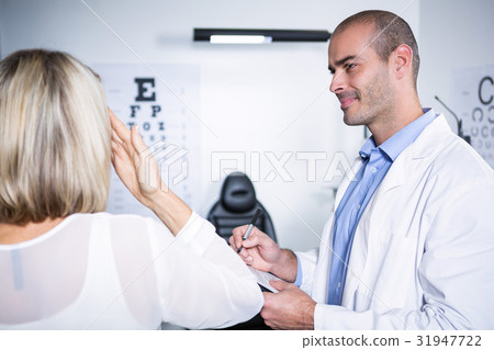 Male optometrist taking eye test of female patient Male optometrist taking eye test of female patient 31947722