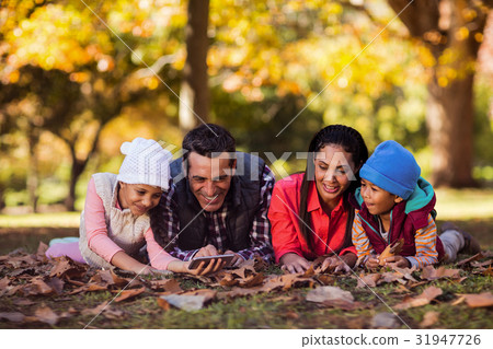 Happy family looking at mobile phone at park 31947726