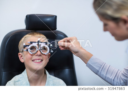 Female optometrist examining young patient with phoropter Female optometrist examining young patient with phoropter 31947863
