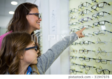 Mother and daughter selecting spectacles from display 31947878