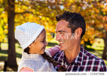 Smiling father carrying daughter at park 31947996
