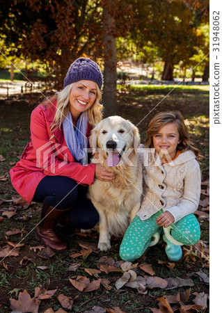 Mother and daughter caressing their dog 31948062
