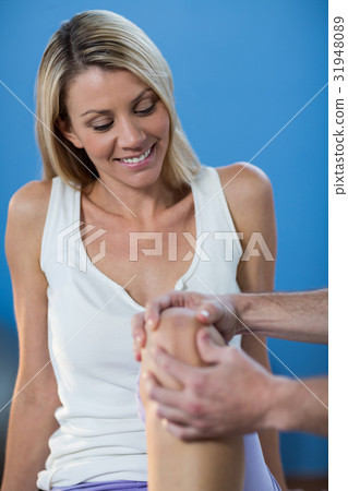 Male physiotherapist giving knee massage to female patient Male physiotherapist giving knee massage to female patient 31948089