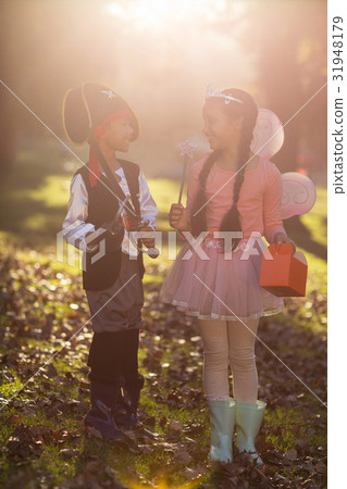 Happy siblings wearing costumes at park Happy siblings wearing costumes at park 31948179