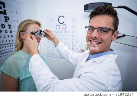 Optometrist examining female patient with phoropter Optometrist examining female patient with phoropter 31948254
