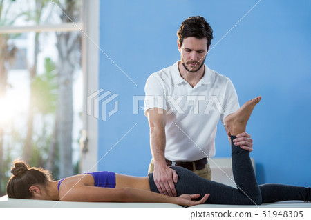 Male physiotherapist giving knee massage to female patient Male physiotherapist giving knee massage to female patient 31948305