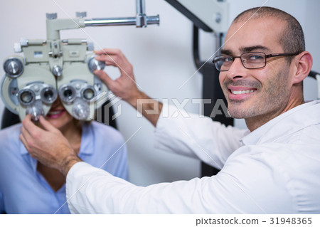 Smiling optometrist examining female patient on phoropter 31948365