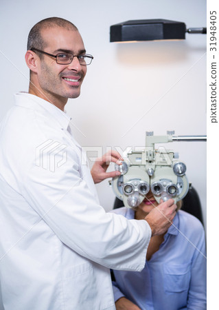 Smiling optometrist examining female patient on phoropter 31948405
