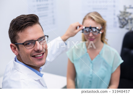 Optometrist examining female patient with phoropter Optometrist examining female patient with phoropter 31948457