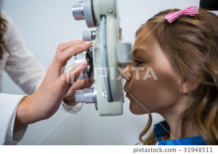 Female optometrist examining young patient on phoropter Female optometrist examining young patient on phoropter 31948511