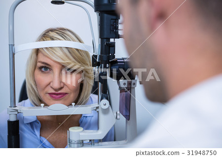 Optometrist examining female patient on slit lamp Optometrist examining female patient on slit lamp 31948750