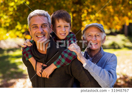 Man piggybacking son while with father at park Man piggybacking son while with father at park 31948767