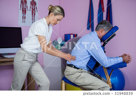 Physiotherapist giving back massage to a patient 31948839