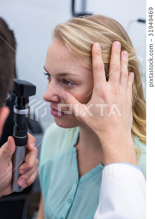 Optometrist examining female patient through ophthalmoscope 31949469