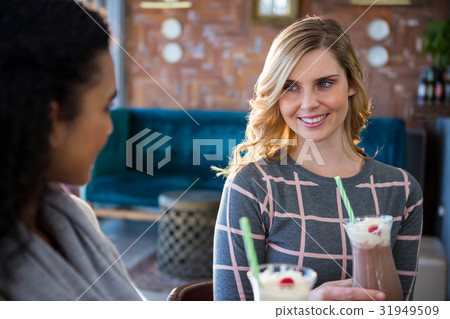 Female friends interacting with each other while having coffee 31949509