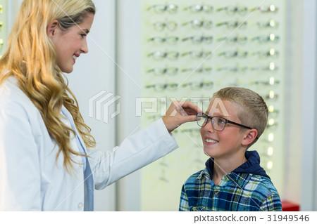Female optometrist prescribing spectacles to young patient 31949546