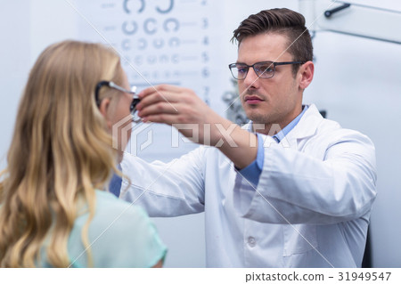 Optometrist examining female patient with phoropter Optometrist examining female patient with phoropter 31949547