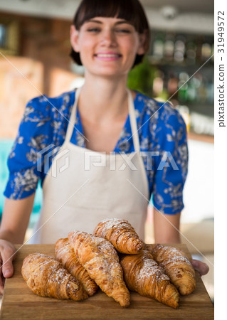 Smiling waitress holding a tray of croissants 31949572