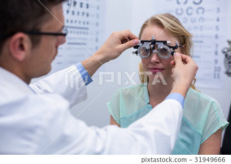 Optometrist examining female patient with phoropter Optometrist examining female patient with phoropter 31949666