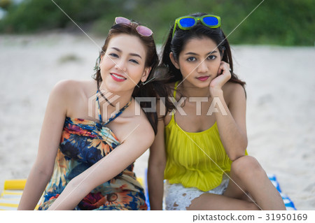 A picture of two beautiful girls sitting on the sand A picture of two beautiful girls sitting on the sand 31950169