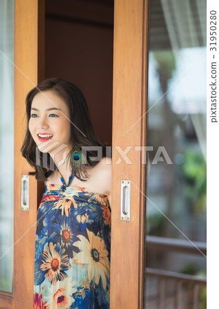 A smiling woman is standing at open door 31950280
