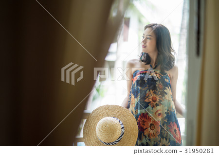 A girl with a hat is looking something in a balcony 31950281