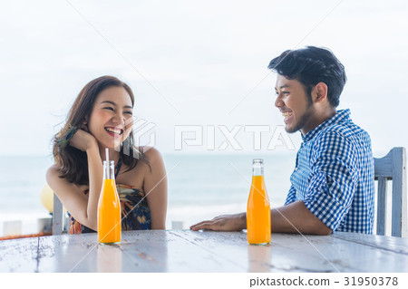 A photo of a couple sitting, talking, smiling near the beach 31950378